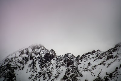 灰蒙蒙的天空下被白雪覆盖的山